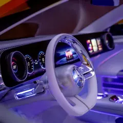 Wnętrze Mercedesa CLA z futurystycznym kokpitem, podświetlanym na niebiesko. Widoczny ekran, kierownica i cyfrowe zegary.