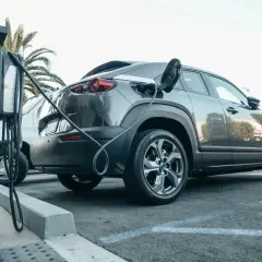 Szary samochód typu SUV z wtyczką ładowania podłączoną do portu. To przykład technologii mild hybrid, która wspomaga silnik spalinowy.