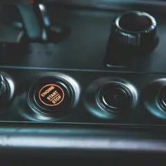 Podświetlany przycisk "ENGINE START STOP" w nowoczesnym samochodzie. Obok niego przyciski wyboru trybu jazdy.