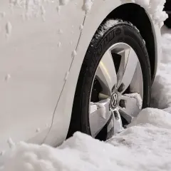 Biały samochód z felgami i oponami Michelin w śniegu. Zastanawiasz się, jakie opony zimowe wybrać?
