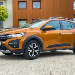 Pomarańczowy Dacia Sandero Stepway na tle nowoczesnego budynku. Zastanawiasz się nad jego spalaniem?