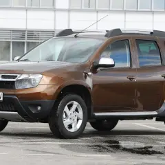 Brązowy Dacia Duster na parkingu. Zastanawiasz się, dacia duster jaki silnik wybrać? Ten model ma napęd 4x4.