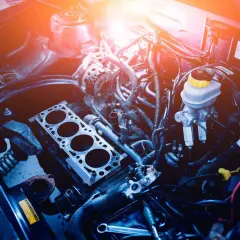 Silnik samochodowy w trakcie naprawy. Zastanawiasz się, ile kosztuje swap silnika? Widoczne części mechaniczne i przewody.