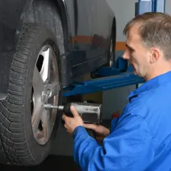 Mechanik w niebieskim kombinezonie dokręca śruby koła. To ważny moment dokręcania docisku sprzęgła LUK.
