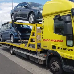 Żółta laweta z autami, w tym Volkswagenem i Skodą. Zastanawiasz się, ile kosztuje sprowadzenie auta z Holandii?