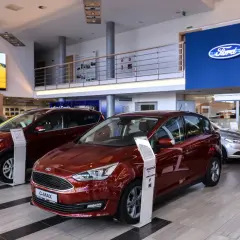 Salon Forda z czerwonym C-Maxem i Kuga na pierwszym planie. Zastanawiasz się, ile można negocjować cenę samochodu?