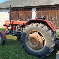 Czerwony Ursus C-330M na trawie, gotowy do pracy. Warto sprawdzić, ile powietrza w oponach Ursus C-360, by zapewnić optymalną przyczepność.