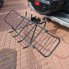 Czarny, metalowy uchwyt do przewozu motocykla na hak, gotowy do montażu przy samochodzie.