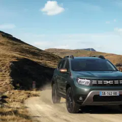 Zielony Dacia Duster off road pokonuje piaszczystą drogę wśród skalistych wzgórz.