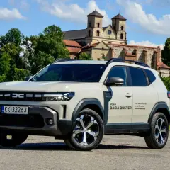 Nowa Dacia Duster hybryda na tle zabytkowego klasztoru.