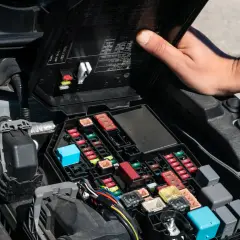 Otwarta skrzynka z bezpiecznikami w komorze silnika Dacia Duster. Widoczny opis bezpieczników i przekaźników.