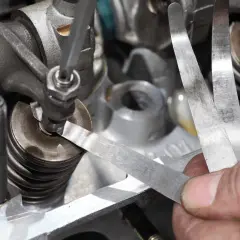 Mechanik sprawdza szczelinomierzem luzy zaworowe. Dowiedz się, ile kosztuje regulacja zaworów w Twoim aucie.