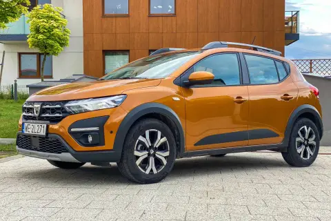 Pomarańczowy Dacia Sandero Stepway na tle nowoczesnego budynku. Zastanawiasz się nad jego spalaniem?