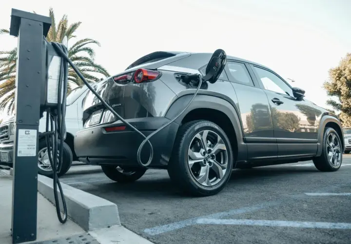 Szary samochód typu SUV z wtyczką ładowania podłączoną do portu. To przykład technologii mild hybrid, która wspomaga silnik spalinowy.