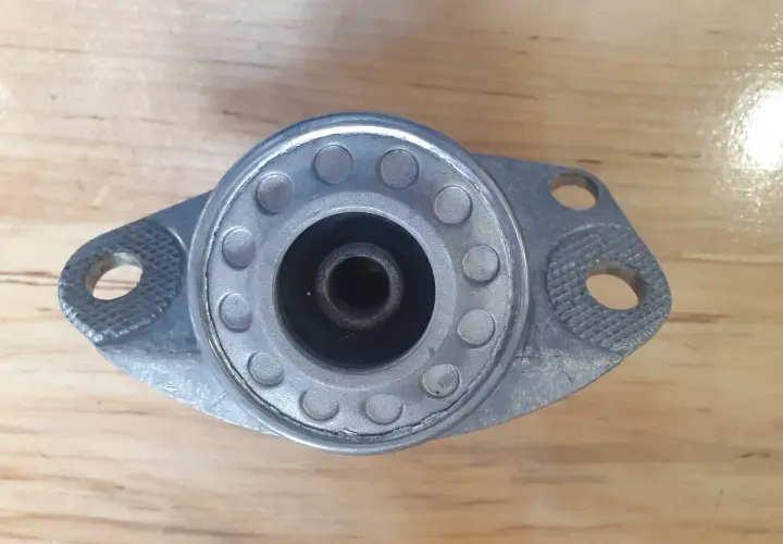 Metalowe górne mocowanie amortyzatora z gumowym elementem centrującym i otworami montażowymi.
