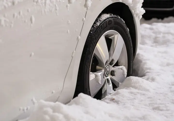 Biały samochód z felgami i oponami Michelin w śniegu. Zastanawiasz się, jakie opony zimowe wybrać?