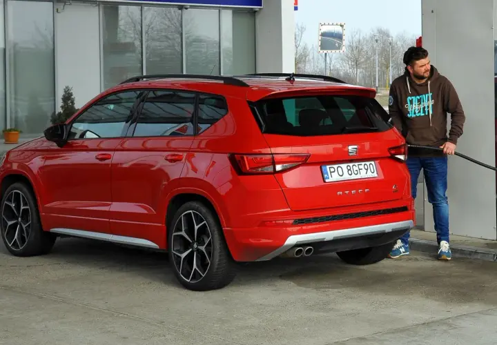 Mężczyzna tankuje czerwonego SUV-a. Zastanawiasz się, ile pali suv? Ten model Seat Ateca właśnie dostaje paliwo.