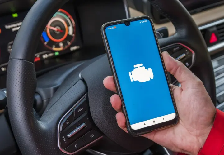 Dacia Sandero z ikoną silnika na ekranie telefonu, gotowa do diagnostyki OBD.
