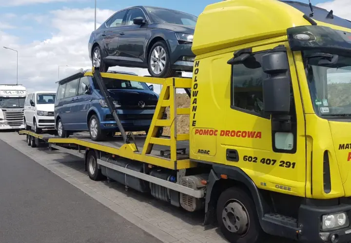 Żółta laweta z autami, w tym Volkswagenem i Skodą. Zastanawiasz się, ile kosztuje sprowadzenie auta z Holandii?
