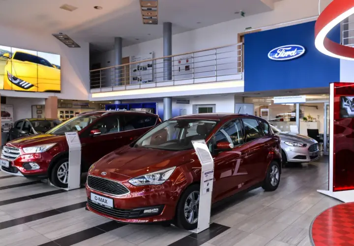 Salon Forda z czerwonym C-Maxem i Kuga na pierwszym planie. Zastanawiasz się, ile można negocjować cenę samochodu?
