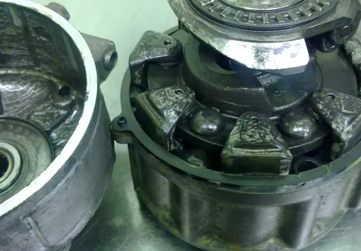 Rozłożone koło pasowe sprężarki klimatyzacji z widocznymi elementami mechanicznymi i łożyskami.