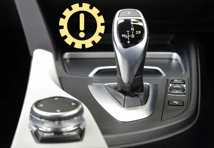 Awaryjne odblokowanie skrzyni biegów w BMW. Ikona ostrzeżenia nad dźwignią zmiany biegów.