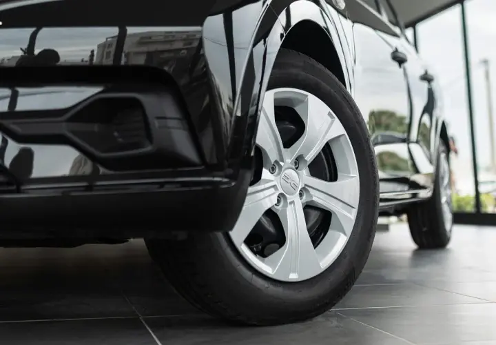 Zbliżenie na przednie koło czarnego Dacia Duster z oponami letnimi. Felga aluminiowa z logo marki.
