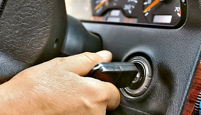 Dłoń przekręca kluczyk w stacyjce. Auto odpala i gaśnie, co frustruje kierowcę.