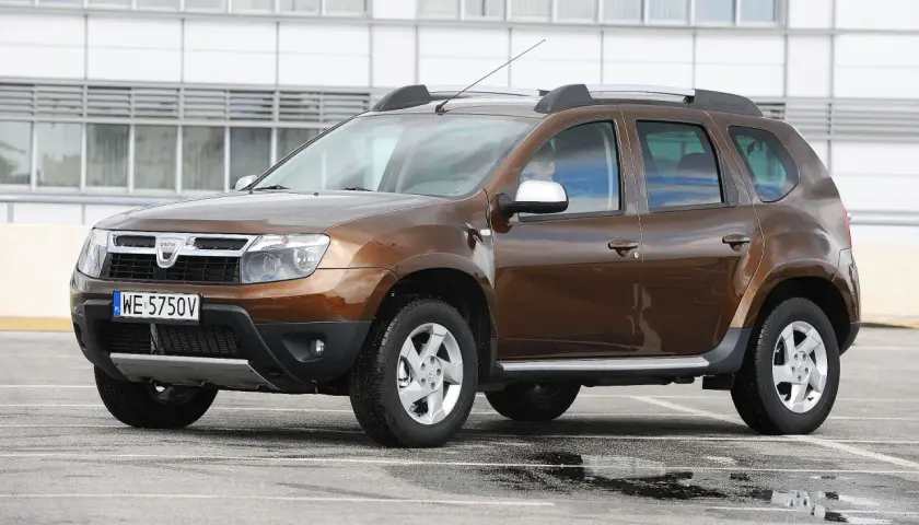 Brązowy Dacia Duster na parkingu. Zastanawiasz się, dacia duster jaki silnik wybrać? Ten model ma napęd 4x4.