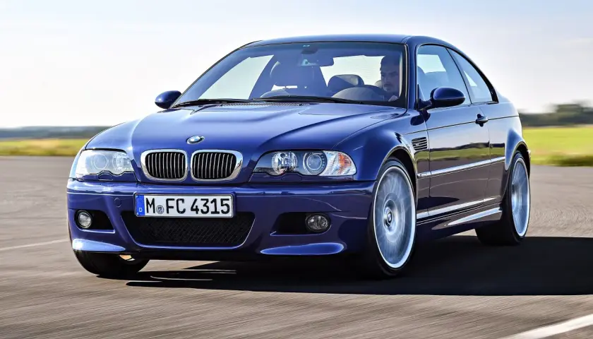 Niebieskie BMW M3 E46, ikona motoryzacji z lat produkcji 2000-2006, pędzi po drodze.