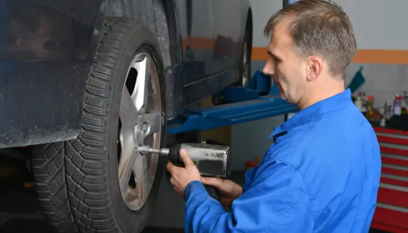 Mechanik w niebieskim kombinezonie dokręca śruby koła. To ważny moment dokręcania docisku sprzęgła LUK.