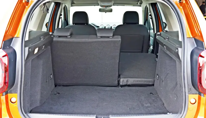 Pusty bagażnik Dacia Duster z opuszczonymi siedzeniami, gotowy na podróż.