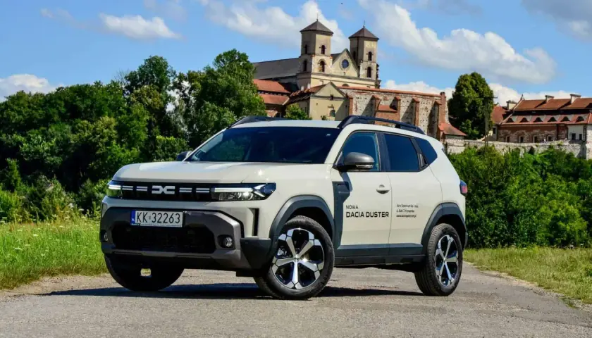 Nowa Dacia Duster hybryda na tle zabytkowego klasztoru.