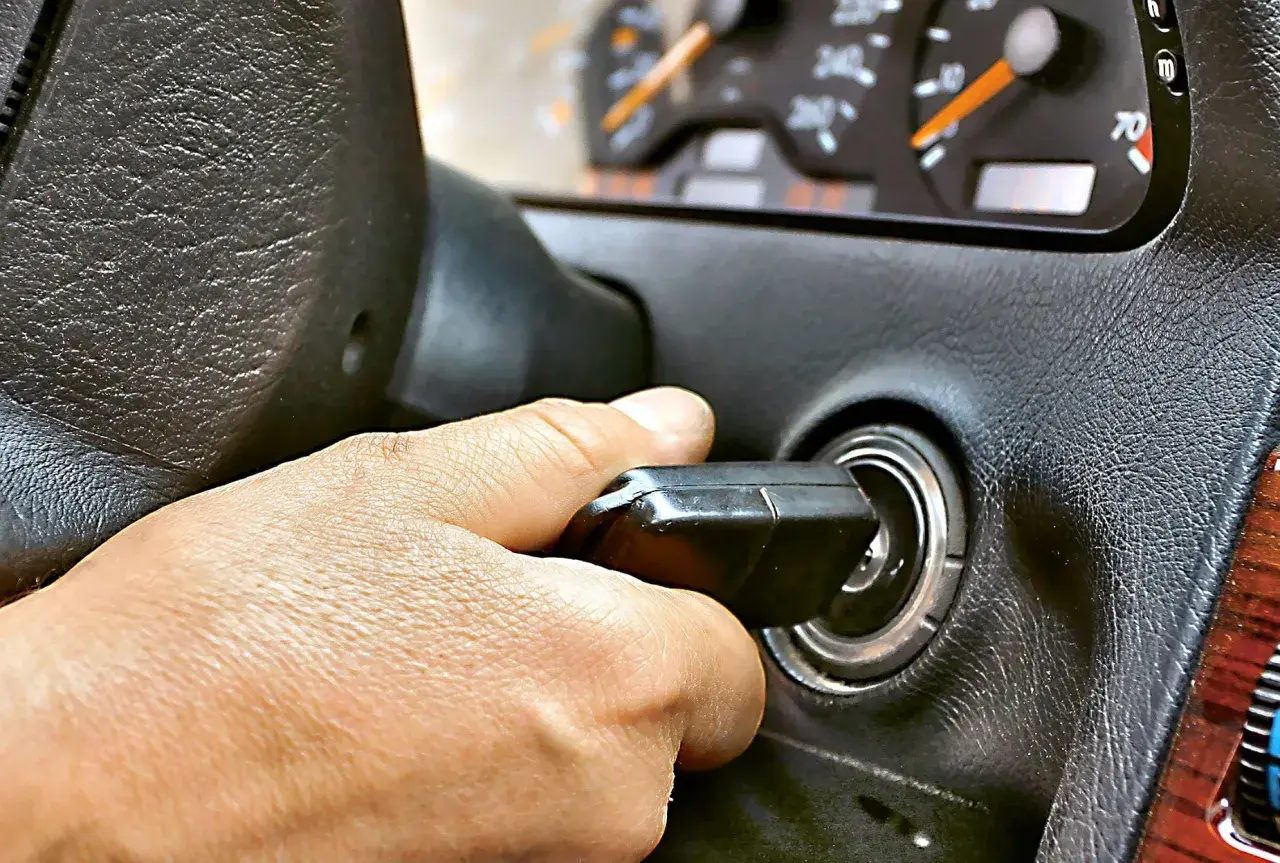 Dłoń przekręca kluczyk w stacyjce. Auto odpala i gaśnie, co frustruje kierowcę.