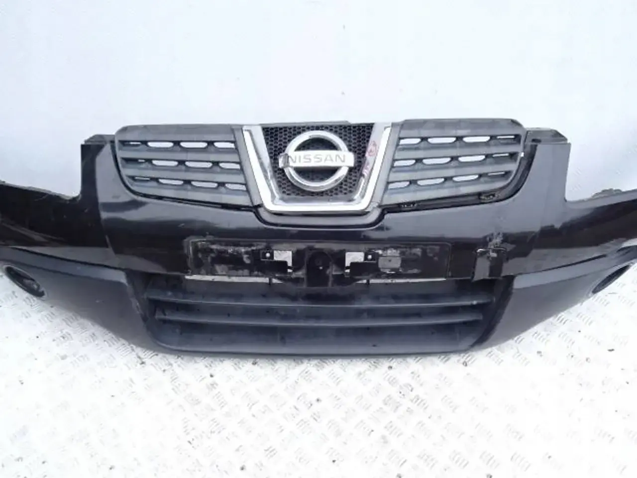 Czarny zderzak Nissan Qashqai z charakterystycznym grillem i logo marki.