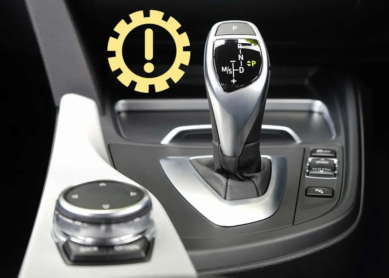 Awaryjne odblokowanie skrzyni biegów w BMW. Ikona ostrzeżenia nad dźwignią zmiany biegów.