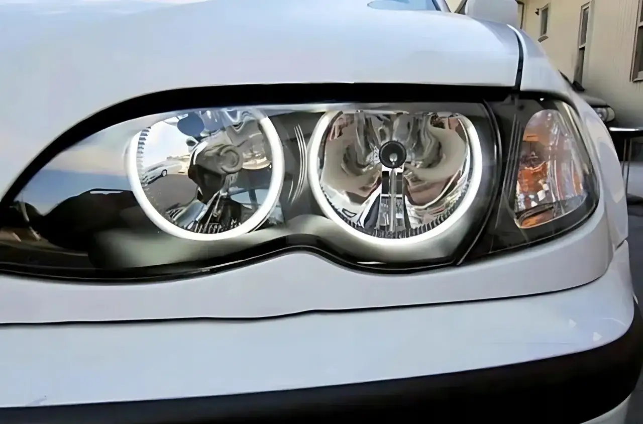 Białe BMW E46 z zamontowanymi ringami w reflektorach, które nadają mu nowoczesny wygląd.
