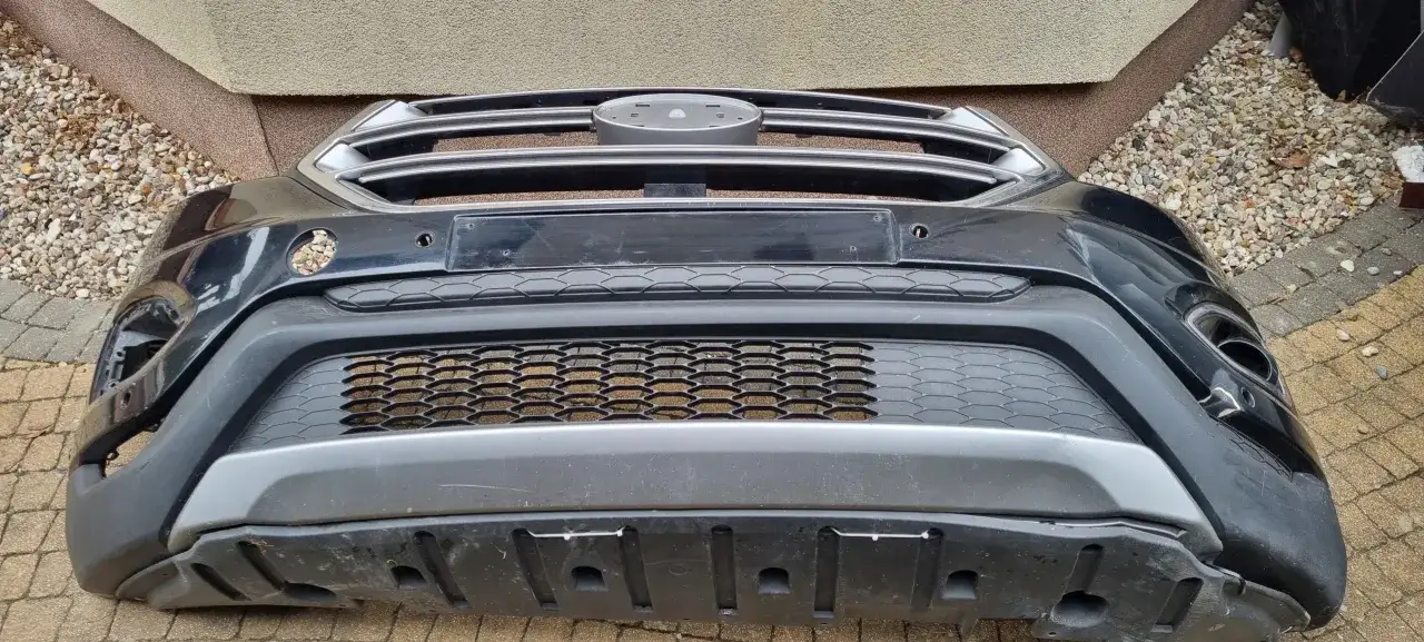 Czarny zderzak Ford Edge z chromowaną atrapą i siatkowymi wlotami powietrza.