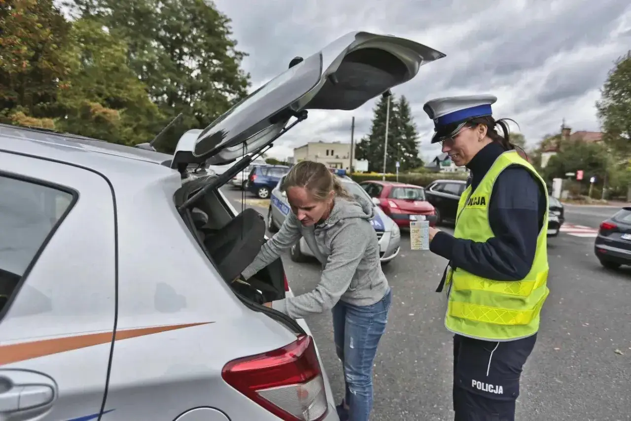 Policjantka sprawdza dokumenty kierowcy, który pakuje bagażnik. To ważny moment, by wiedzieć, jak obliczyć ładowność pojazdu.
