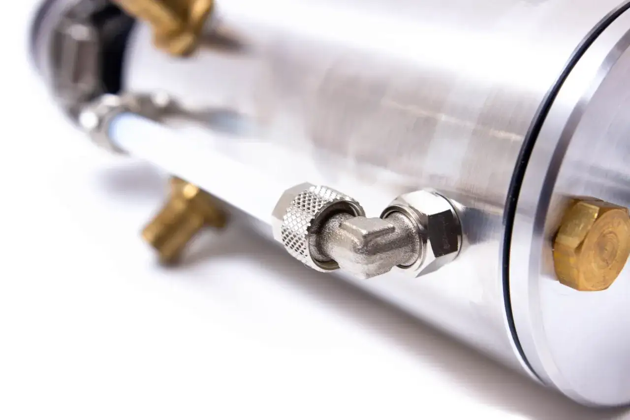 Metalowy cylinder z mosiężnymi złączkami i białym przewodem, element konstrukcyjny do separatora oleju.