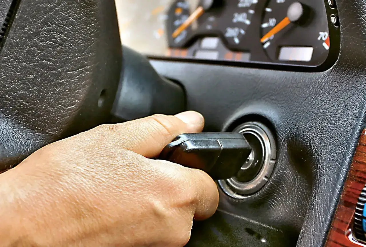 Dłoń przekręca kluczyk w stacyjce. Auto odpala i gaśnie, co frustruje kierowcę.