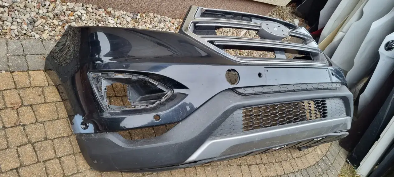 Czarny zderzak Ford Edge z chromowaną atrapą i miejscem na czujniki parkowania.