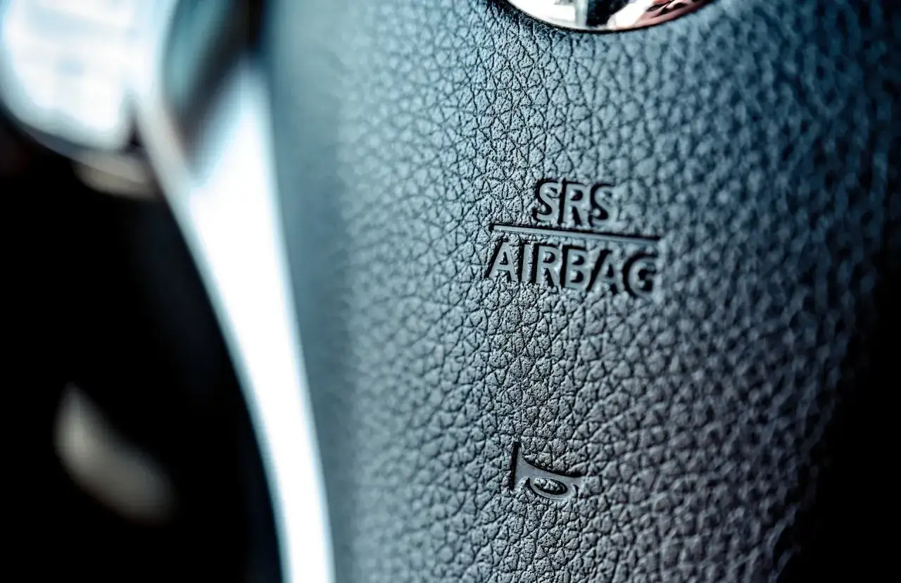 Zbliżenie na kierownicę z napisem SRS AIRBAG. Kontrolka błędu poduszki powietrznej może oznaczać problem z tym kluczowym systemem bezpieczeństwa.