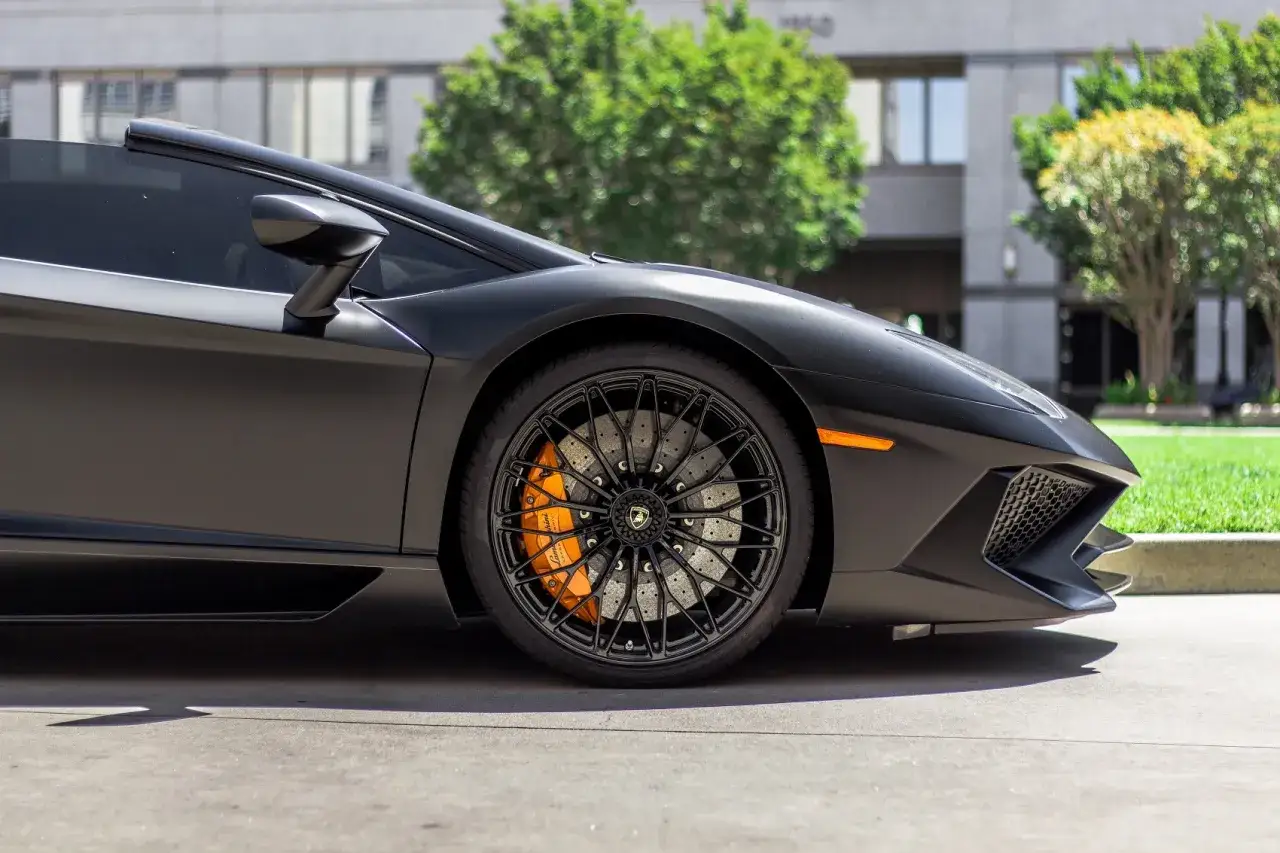 Jaki kolor zacisków do czarnego auta? Pomarańczowe zaciski hamulcowe kontrastują z matową czernią Lamborghini, dodając mu sportowego charakteru.