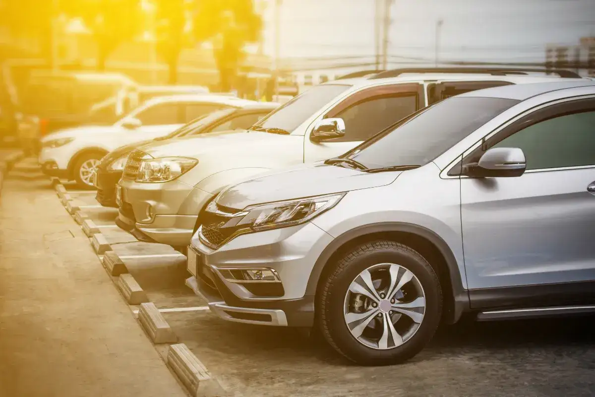 Rząd zaparkowanych samochodów, od srebrnego SUV-a po jasne auto. Zastanawiasz się, ile można negocjować cenę samochodu?